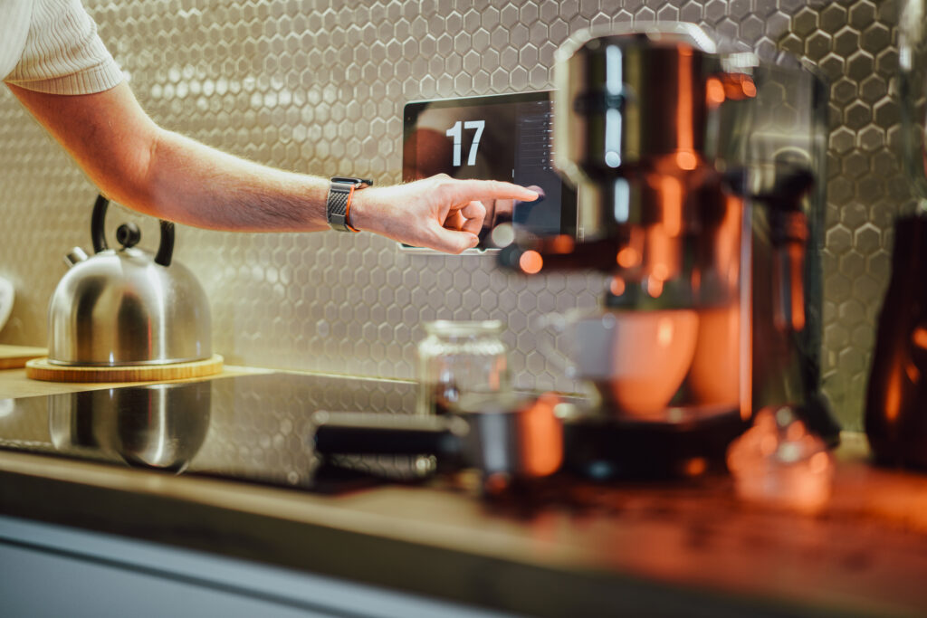 Smart home. Touch screen operation in a modern kitchen. Coffe machine. Home automation.  A hand operating a touch screen.